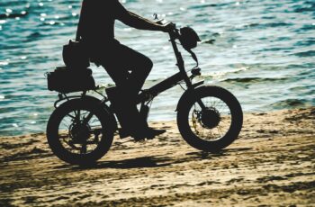 Image of person riding a folding fat tire electric bike on a beack.
